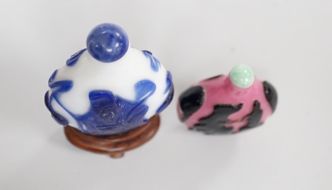 Two Chinese overlay glass snuff bottles, the black and pink bottle in imitation of shadow agate, 18th century, decorated with an eagle and the moon the reverse with a dog tied to a chain, 4.3cm, the blue and white exampl